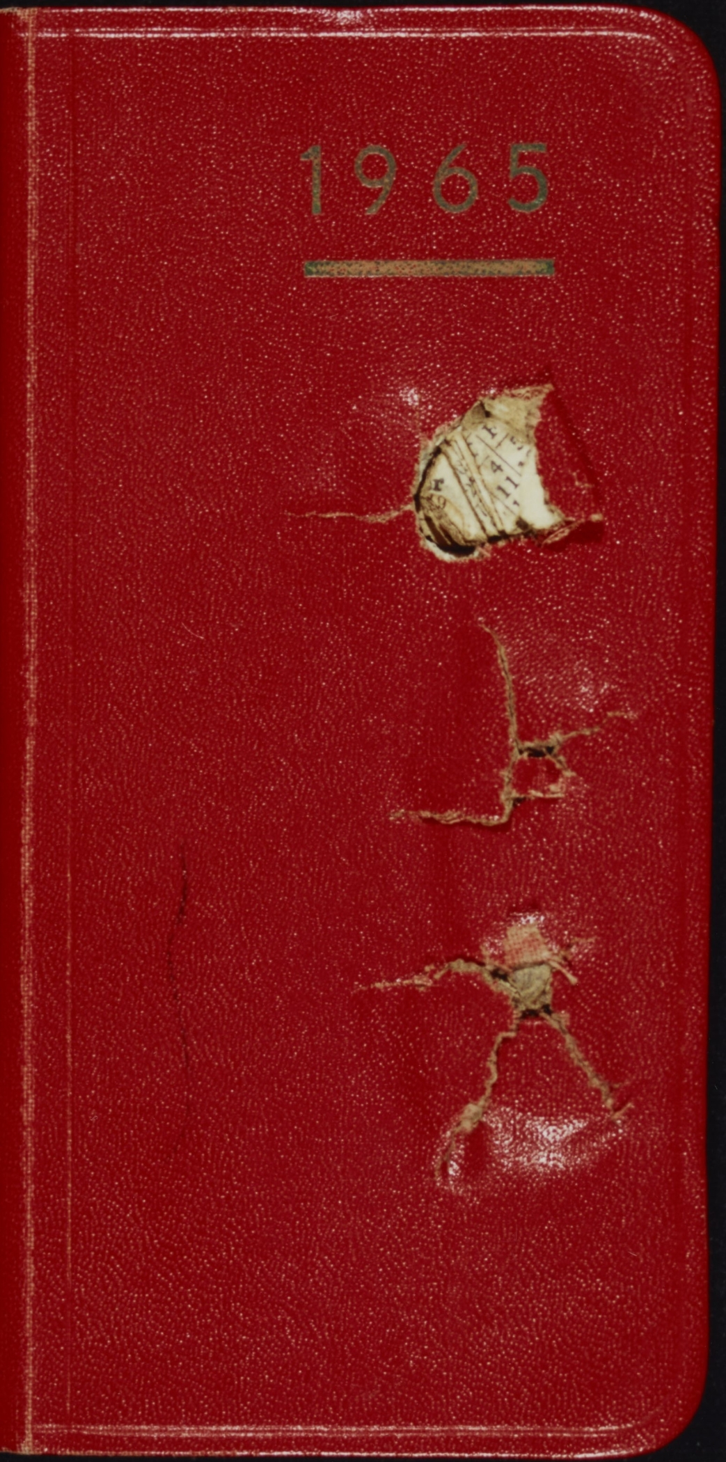 Red cover of pocket-size address book with two bullet holes