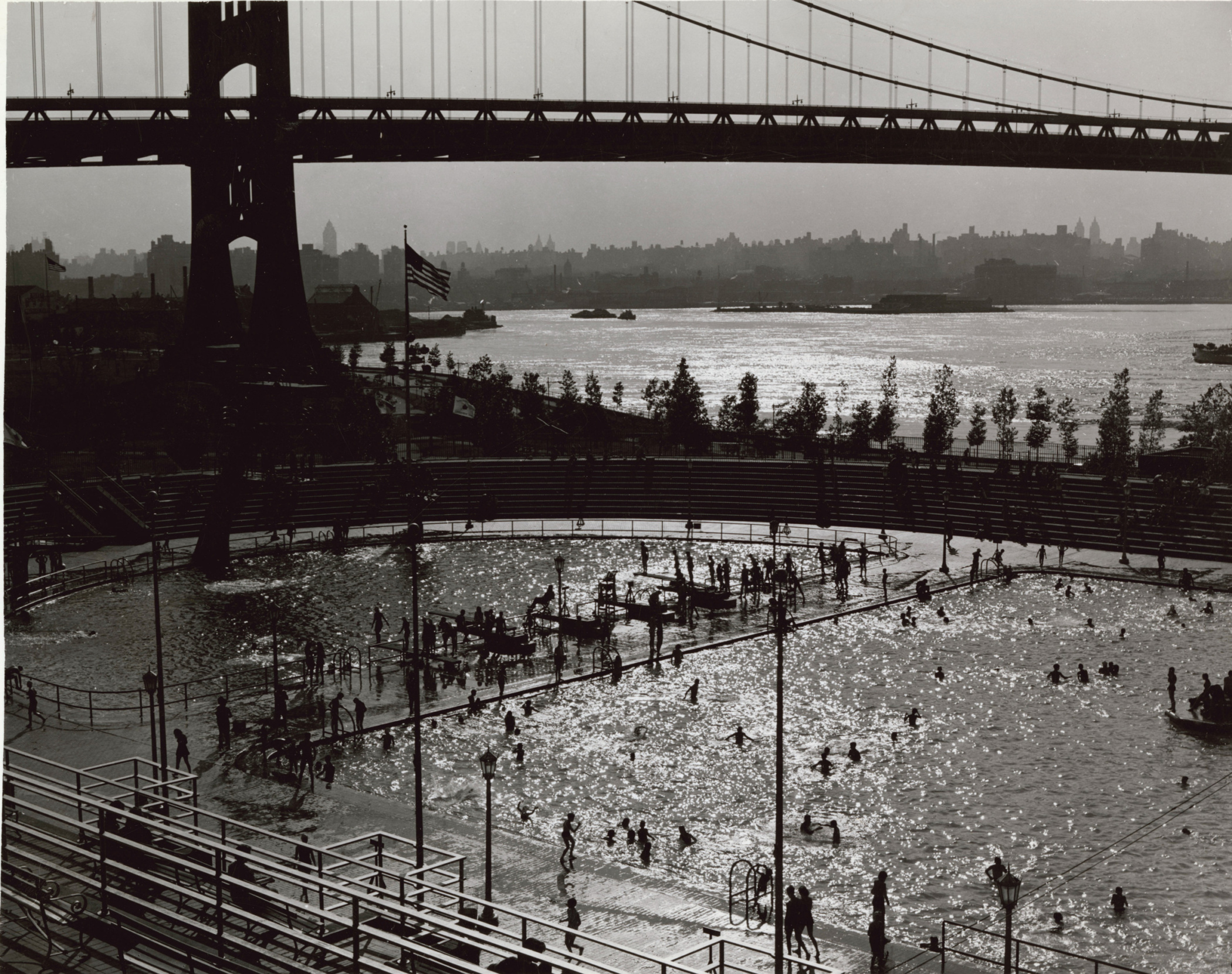 Black and white photograph showing pool area in Astoria Park with the Triborough Bridge in the background.