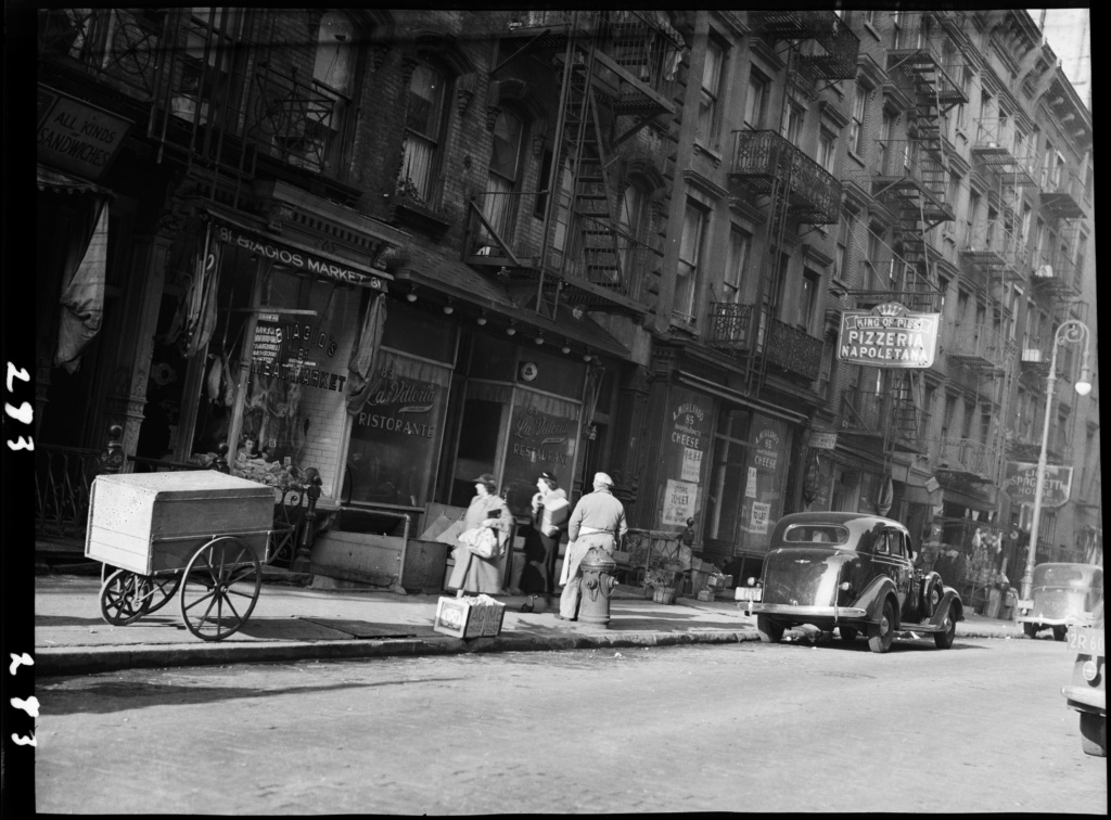 Historic street scene in Little Italy, New York City, with storefronts, pedestrians, and lively neighborhood activity.